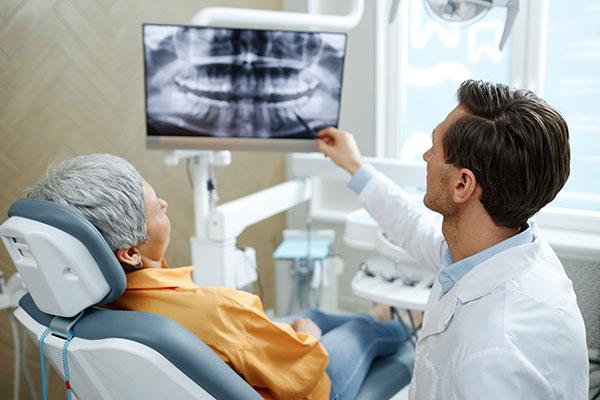  A smiling patient and a friendly dentist looking at a dental X-ray in a modern, clean examination room at Studio Smiles in Los Angeles.